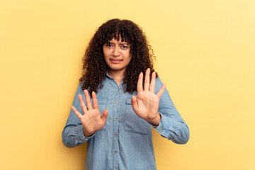 Young mixed race woman isolated on yellow background rejecting someone showing a gesture of disgust.