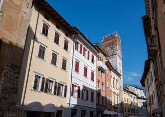 Fototapeta na wymiar Trento, Italy, June 2021. In the historic center a medieval tower stands out among the brightly colored facades of the houses. Beautiful summer day.