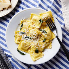 ravioli with butter parmesan and sage dish on a blue stripe tablecloth