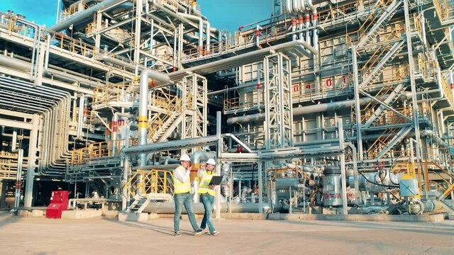 Two workers are walking through the premises of the oil refinery