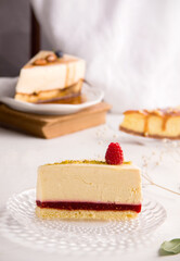 Vanilla cheesecake with raspberry jam on a light background with pieces of other desserts