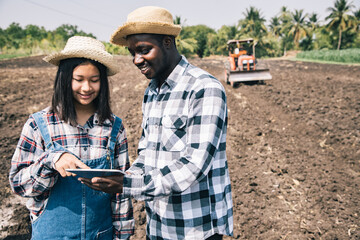 Young girls consulted and planned the planting of corn or green beans using a computerized tablet with Africa America’s father was plowing the soil with a tractor in corn farm. Successful concept