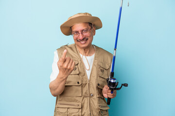 Senior indian fisherman holding rod isolated on blue background pointing with finger at you as if inviting come closer.
