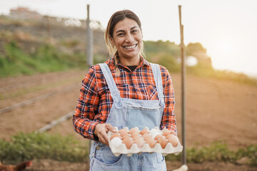 Mature latin woman holding fresh eggs - Elderly farmer person smiling in camera © Sabrina