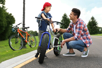 Obraz na płótnie Canvas Dad teaching son to ride bicycle outdoors