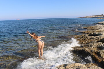 Young brunette girl on rocks beach in Malta, untouched nature