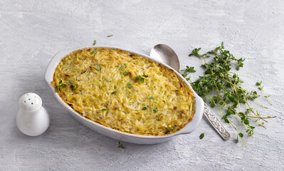 Cabbage casserole with lentils and cream, garnished with thyme in a ceramic baking dish on a light gray background, top view	