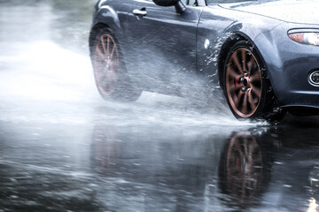 Sports car driven on rainy roads close up on a wheel with motion blur effect