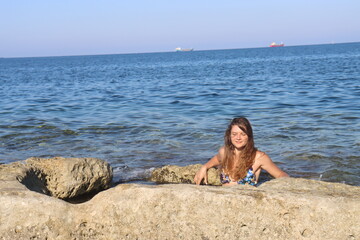 Young brunette girl on rocks beach in Malta, untouched nature