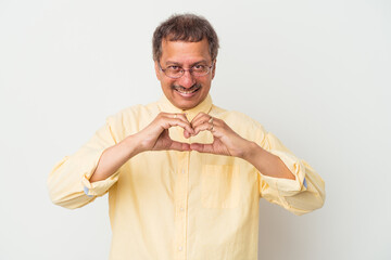 Middle aged indian man isolated on white background smiling and showing a heart shape with hands.