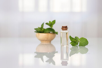 Mint essential oil in a small bottle on a glass table.
