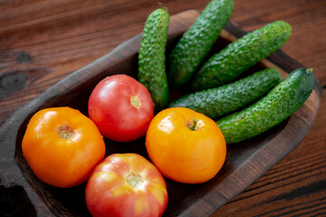 Fresh cucumbers and tomatoes on a wooden background.