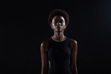 Portrait of standing african american woman with afro hairstyle on black studio background.