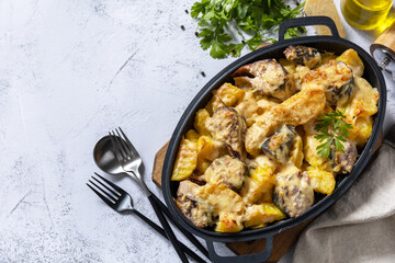 Baked mackerel with potatoes and cheese on a marble tabletop.