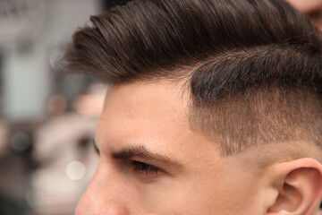 Handsome man with stylish haircut in salon, closeup