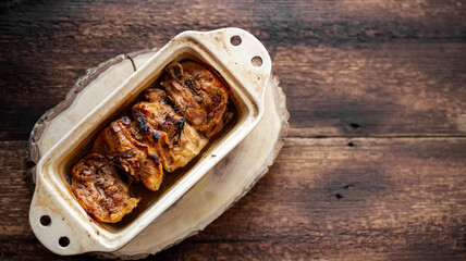 Baked fried chicken thighs in a baking dish on a wooden background. Place for your text.