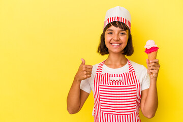 Young mixed race ice cream maker woman holding an ice cream isolated on yellow background smiling and raising thumb up