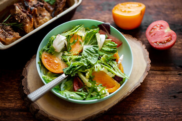 Healthy salad of fresh vegetables, herbs and tomatoes on a wooden background.