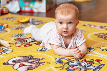 A small child on a rug among toys