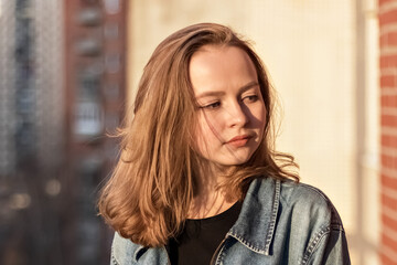 Portrait of a young teenage girl against a brick wall at sunset
