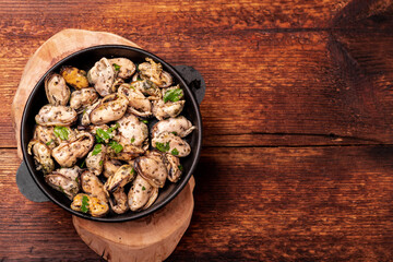 Peeled mussels in sauce on a dark wooden background. Place for your text.