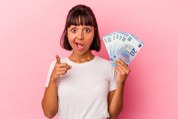 Young mixed race woman holding bills isolated on pink background having an idea, inspiration concept.