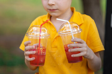 Young redhead boy holding lemonade outdoors. Summer refreshing drink.