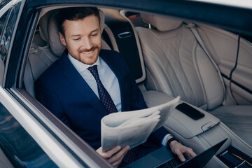 Relaxed entrepreneur reading newspaper while riding in limousine