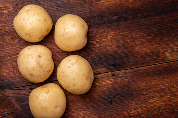 Tubers of large young potatoes on a wooden background.