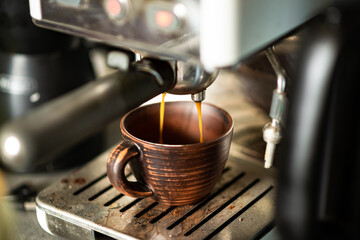 Coffee is prepared in a coffee machine. Freshly made coffee is poured into an earthenware cup.