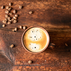 Cup with coffee and coffee beans on a wooden background.