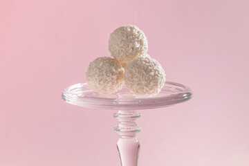 round sweet candies in coconut flakes on a pink background, taste harmony, exquisite dessert, rafaello