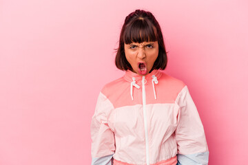 Young mixed race woman isolated on pink background shouting very angry, rage concept, frustrated.