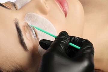 Young woman undergoing eyelash lamination, closeup. Professional service