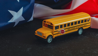 School bus and American flag. 
School bus and American flag lie on a black background, close-up...