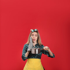 Obraz premium Young housewife with saucepan on red background