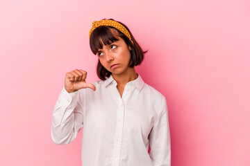 Young mixed race woman isolated on pink background showing a dislike gesture, thumbs down....