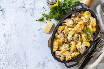 Baked mackerel with potatoes and cheese on a marble tabletop.