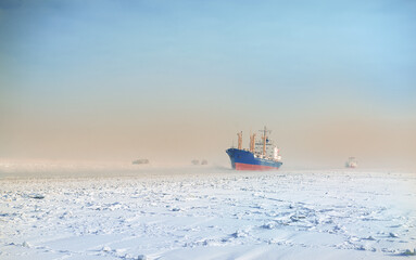 Winter shipping. Big cargo ship in ice sea fairway .