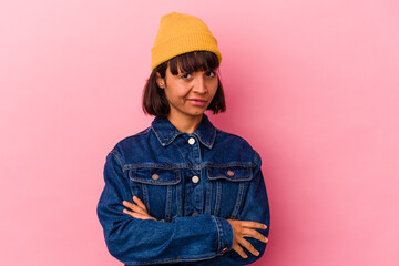 Young mixed race woman isolated on pink background suspicious, uncertain, examining you.