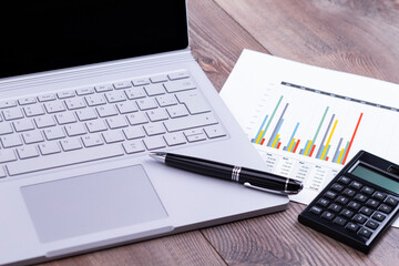 The photo shows a business workstation with computer, calculator and pen on a wooden work table