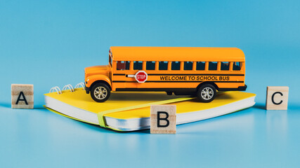 
School bus and notebook on blue. 
School bus, notebook and wooden cubes with letters on a blue...