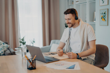 Smiling young male in headset studying at home during quarantine