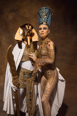 Obraz premium Young woman in image of Nefertiti in art performance isolated on brown vintage background. Retro style, comparison of eras concept.