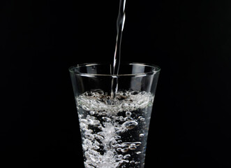 Pour water into a separate glass on a black background.