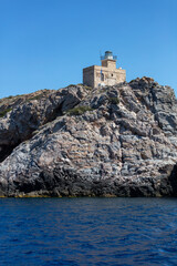 Fototapeta na wymiar Lighthhouse building on a rocky cliff. Ios island Greece. Cyclades