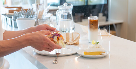 カフェのカウンター席で、サンドイッチを食べる人の手のアップ