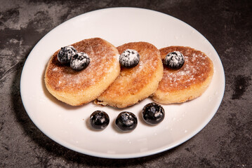 Cheesecakes (curd pancakes) with blueberries on a white plate. Healthy tasty breakfast. Close-up