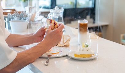 カフェのカウンター席で、サンドイッチを食べる人の手のアップ