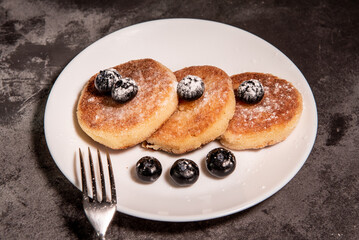 Cheesecakes (curd pancakes) with blueberries on a white plate. Healthy tasty breakfast. Close-up